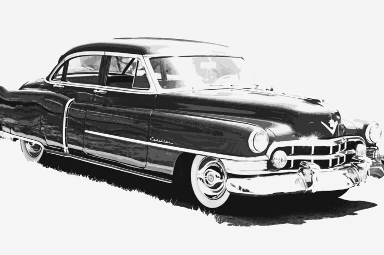 Black and white illustration of a vintage Cadillac car, viewed from the front left side, showing its classic round headlights, chrome details, and smooth, curved body lines against a plain background.