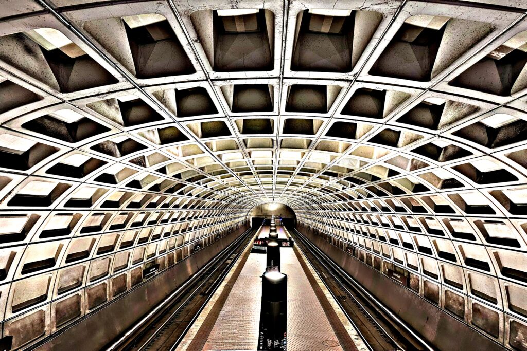 A symmetric view down a Metro station platform featuring a curved, coffered concrete ceiling.